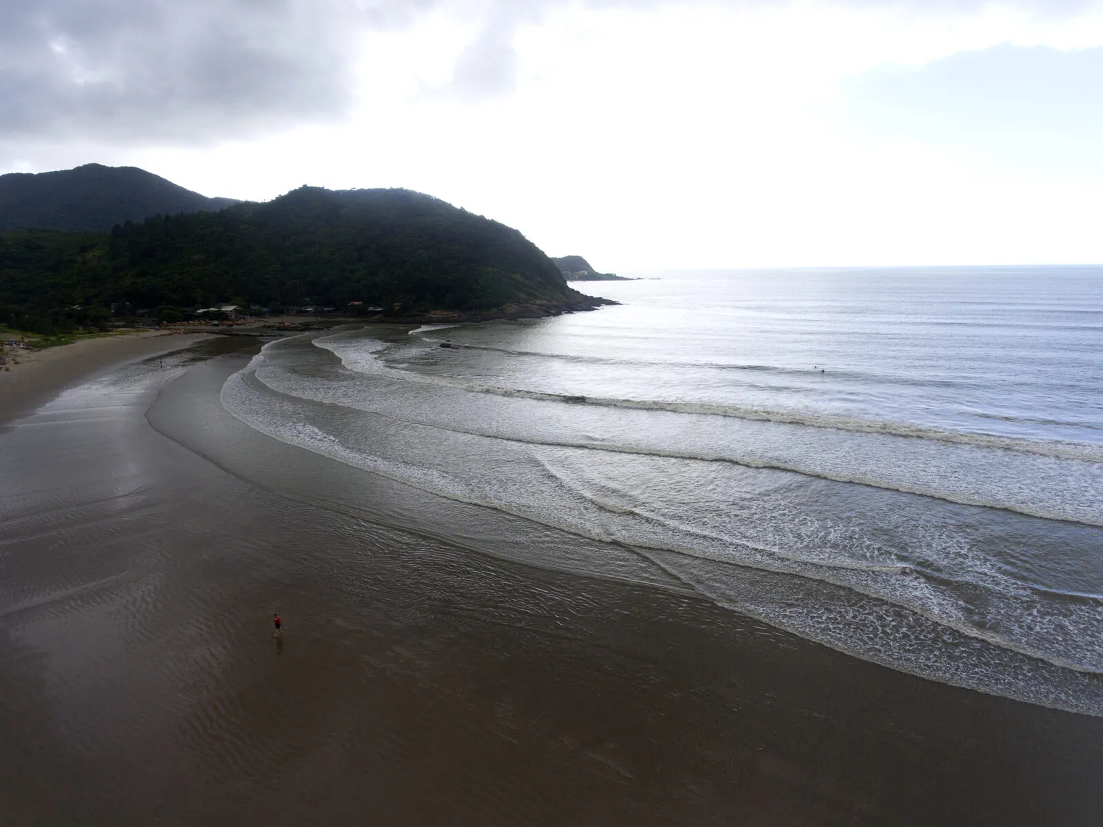 Vista aérea da praia de Gravatá, em Navegantes, com faixa extensa de areia clara, ondas e mar aberto ao entardecer
