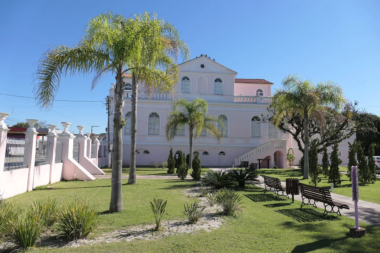 Casarão Gallotti, casarão histórico de fachada rosa tombado pela Fundação Catarinense de Cultura, no centro de Tijucas, cercado por palmeiras e jardim